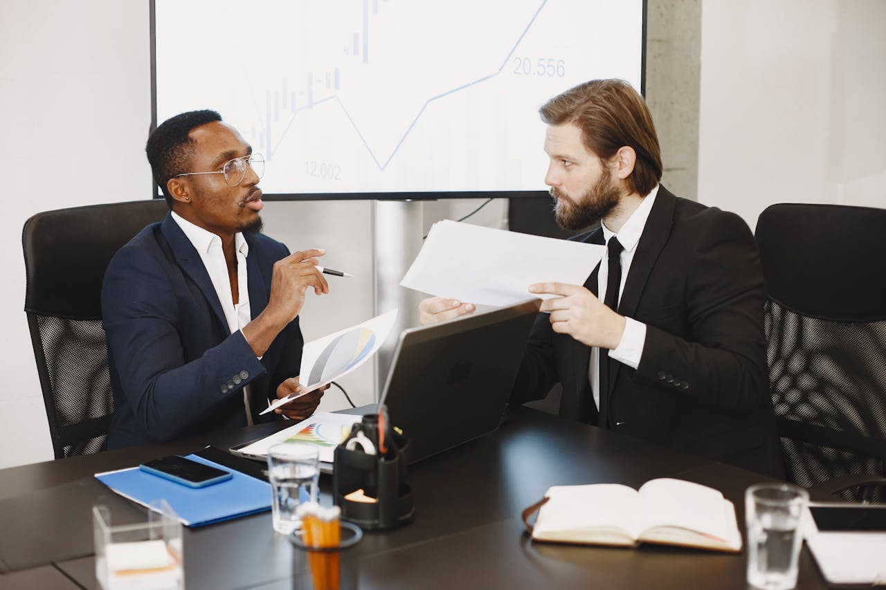Two business professionals engaged in a planning meeting, discussing documents in a modern office setting.